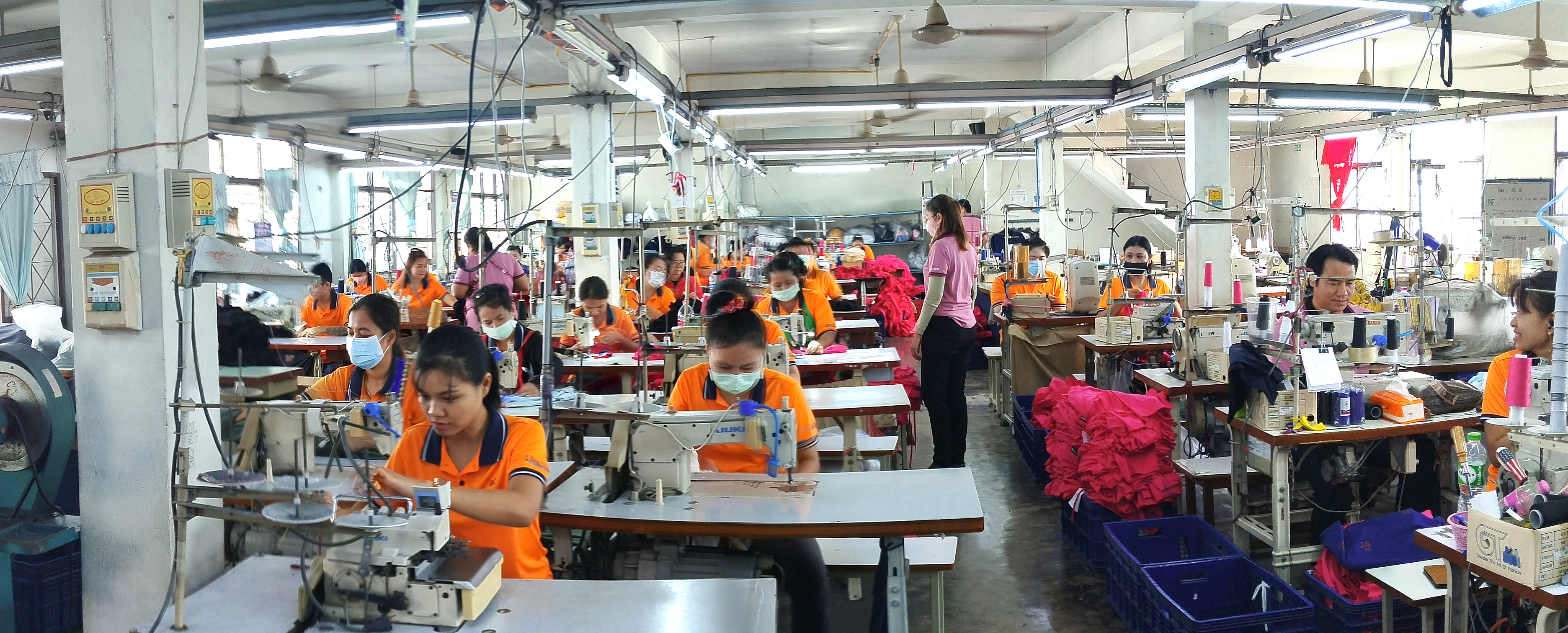 ไลน์เย็บในโรงงาน: พนักงานกำลังเย็บเสื้อด้วยเครื่องจักรอุตสาหกรรม บรรยากาศสะอาดเป็นระเบียบ